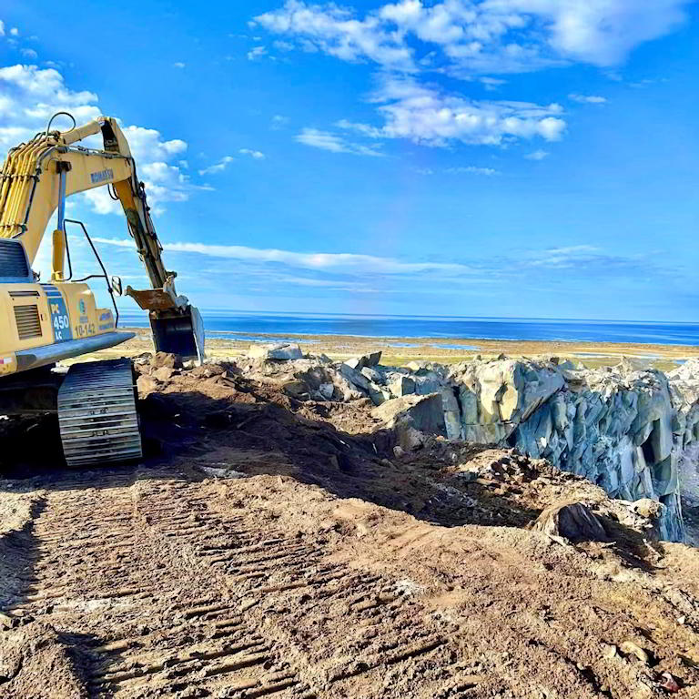 Excavator at coastal construction site
