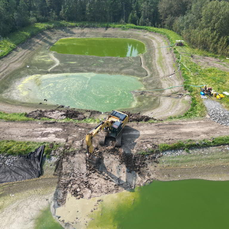 Excavator dredging pond