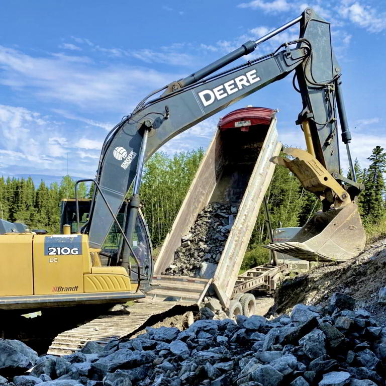 Excavator loading rock into dump trailer