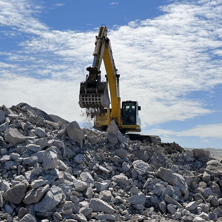 Excavator operating rock pile